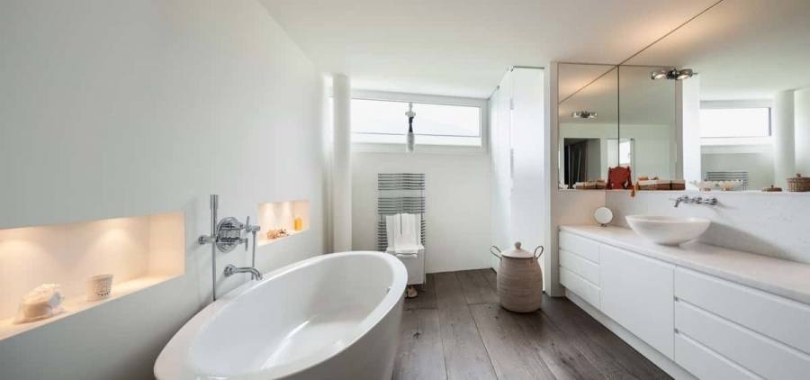 Simple side table with glass top next to the white standalone bathtub [Design: James