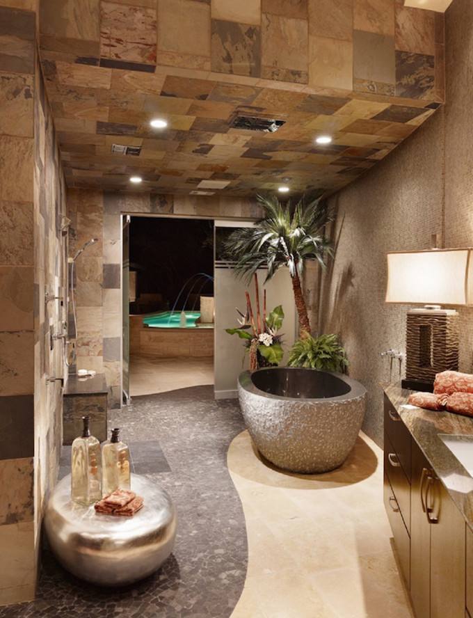 Half wall in natural stone and pebbles on the floor turn the the small bathroom into