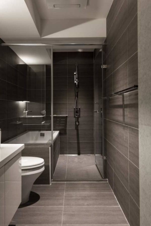 rectangle white bathtub with black tile connected by black tile wall