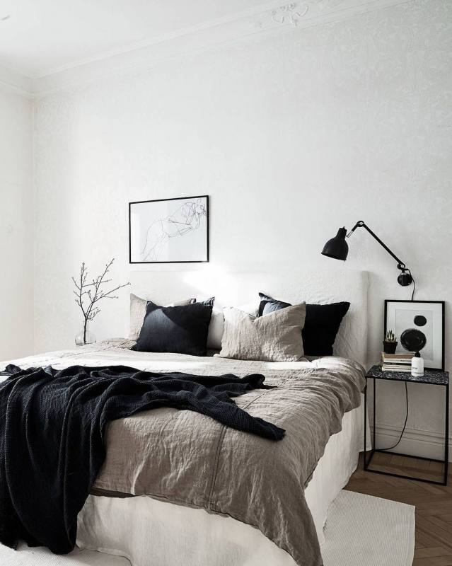 Enhance the brightness in a room with black walls by using a white  bedspread and bright red accents throughout the room