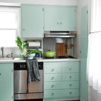 Hunter green kitchen cabinets with a brass sink faucet, pendant lights and  hardware atop carrera marble counters