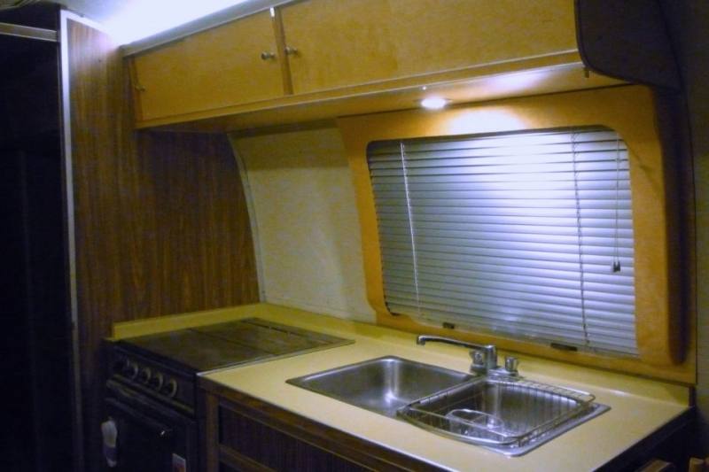 Elegant kitchen features a Wolf Range situated under a bank of windows  dressed in light bamboo roman shades as well as a ceiling mount vent hood